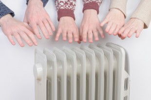 Family warming up hands over electric heater