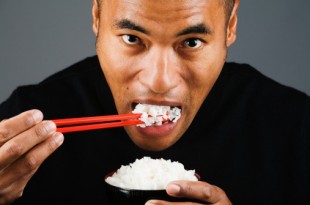 Asian man eating rice with chopsticks