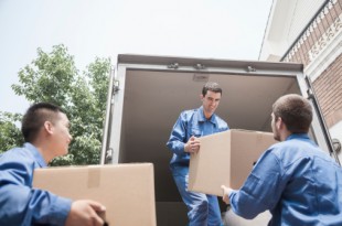 Movers unloading moving van, passing a cardboard box